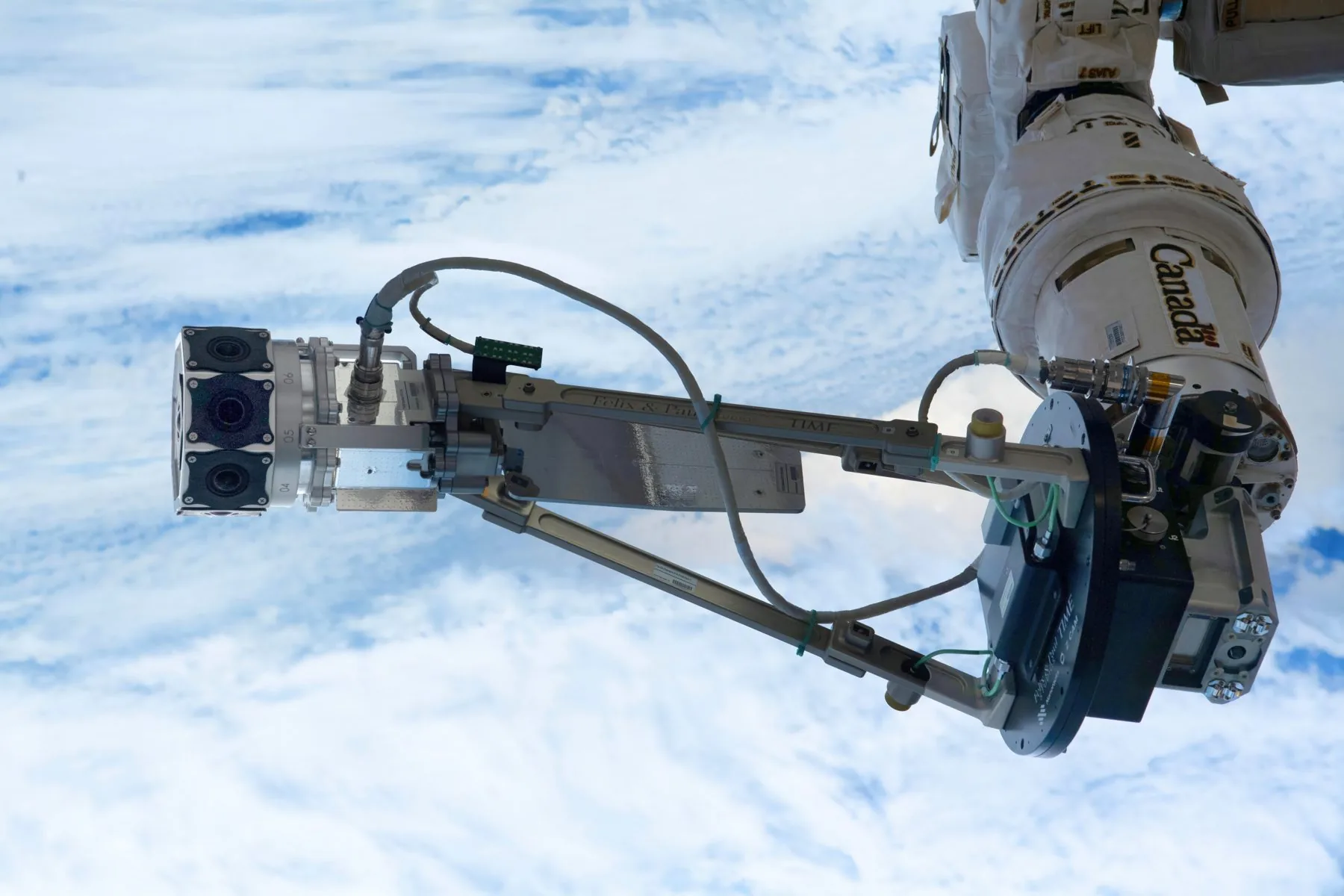 The Space Explorers spacewalk camera on the robotic arm above Earth